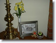 DSC02247 * On the end table next to the sofa, a vase of daffodils and a glass chocolate egg next to a favorite photo of Baby Grimaldi.  The glass egg is what Barb often used as a model for her chocolate egg cake - an annual Easter dessert. * On the end table next to the sofa, a vase of daffodils and a glass chocolate egg next to a favorite photo of Baby Grimaldi.  The glass egg is what Barb often used as a model for her chocolate egg cake - an annual Easter dessert. * 1280 x 960 * (617KB)